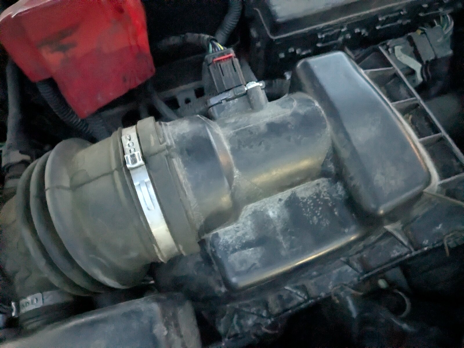 Photo of the mass air flow sensor mounted in the air cleaner housing, upstream of the throttle body.