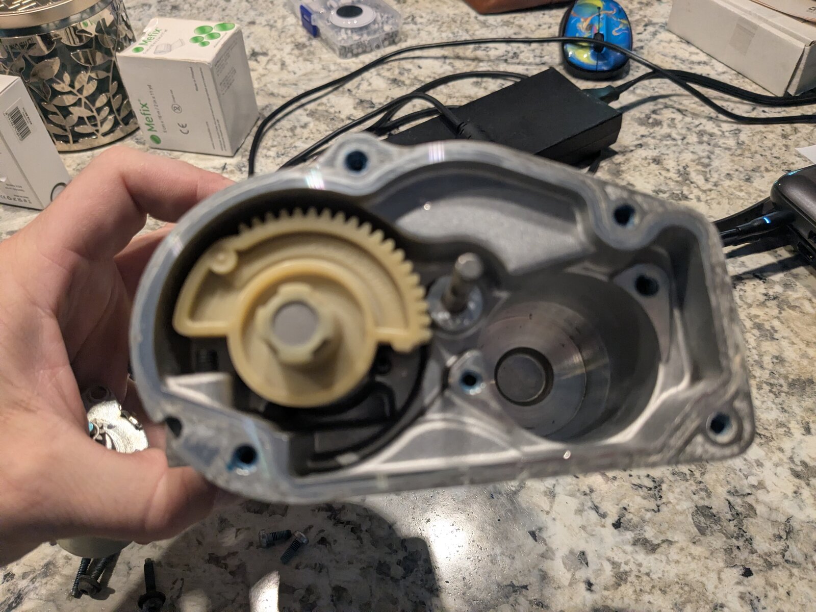 Aluminum housing with the gear train removed, showing the empty gear cavity, the throttle shaft, and the cylindrical bore that the actuator motor seats into.