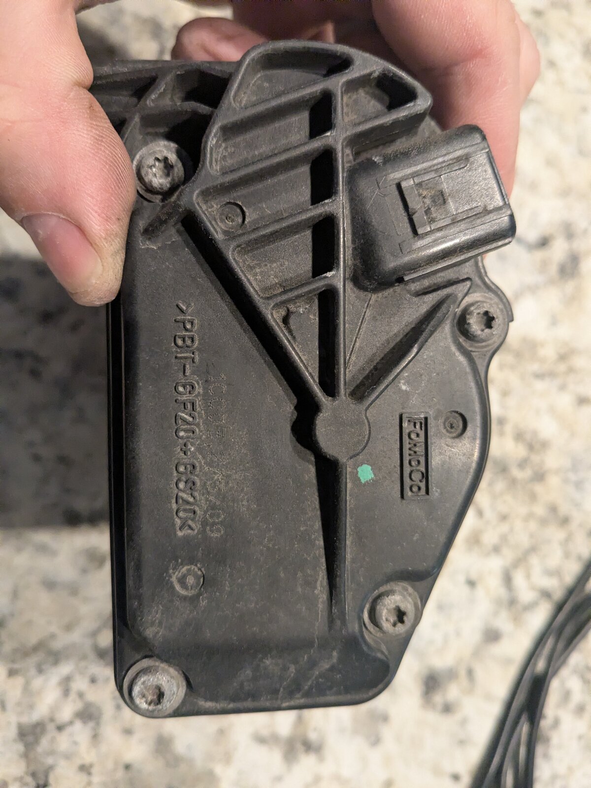Back of the black plastic motor housing cover, stamped PBT-6F20-6S20 with a FoMoCo logo, showing the electrical connector and mounting screws.