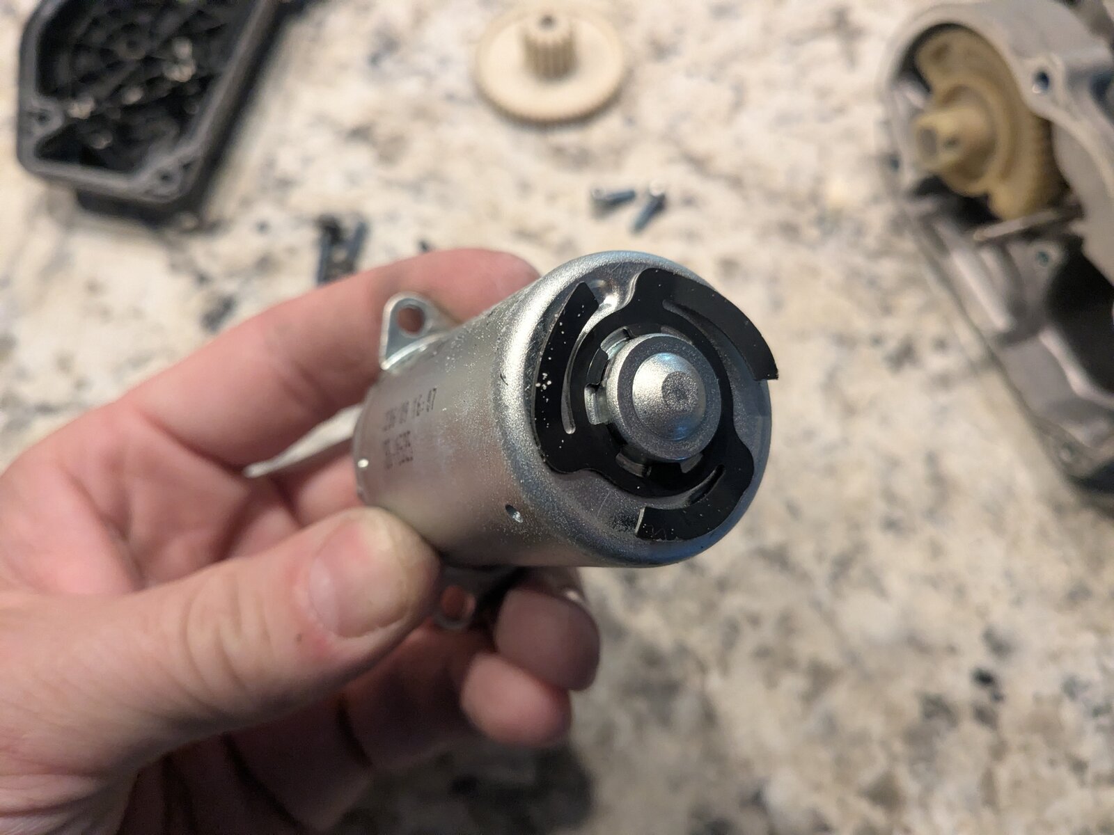 Side of the actuator motor stamped with a manufacturer part number and a mounting bracket tab.