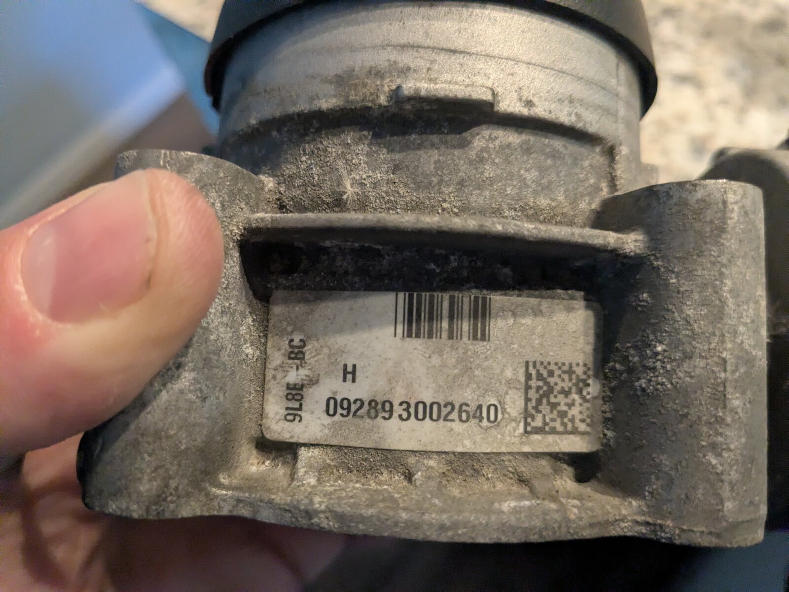 Close-up of the throttle body's part label, printed with a linear barcode, a 2D data matrix code, and the text 9L8E-9F991-BC.